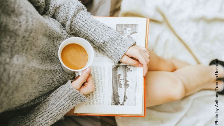 Frau liest ein Buch mit einer Tasse Kaffee