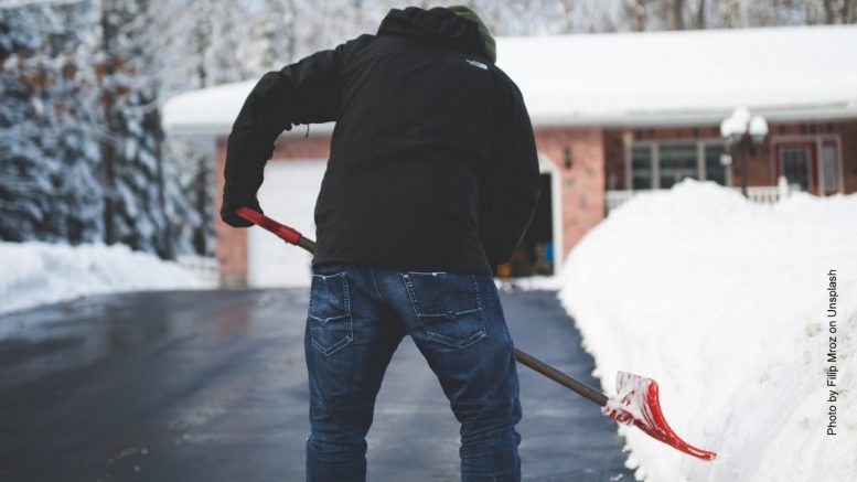 Mann räumt den Schnee einer Ausfahrt weg