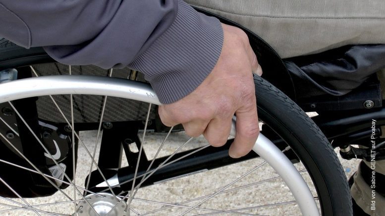 Rollstuhl - Detailaufnahme mit Hände am Laufrad