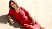 Frau im roten Kleid am Strand liegend, Modefoto