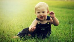 Kleines Kind in Jeanslatzhose im Gras
