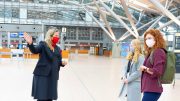 Corona-Pandemie, alle tragen am Hamburg Airport Mundschutz. Zwei Reisende fragen eine Airport-Mitarbeiterin