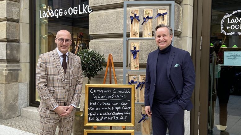 Zwei Männer am Werbeschild vor dem GEschäft von Ladage & Oelke