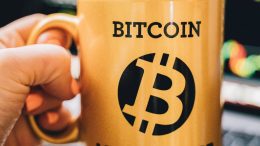 Gelber Kafferbecher mit Aufschrift Bitcoin Millionaire und Bitcoin Logo