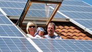 Familie schaut aus einem Dachfenster. Dach mit Solarstrommodulen