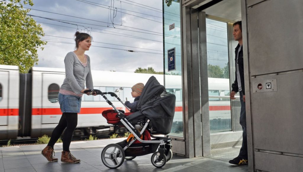 Frau mit einer Kinderkarre fährt zum Fahrstul