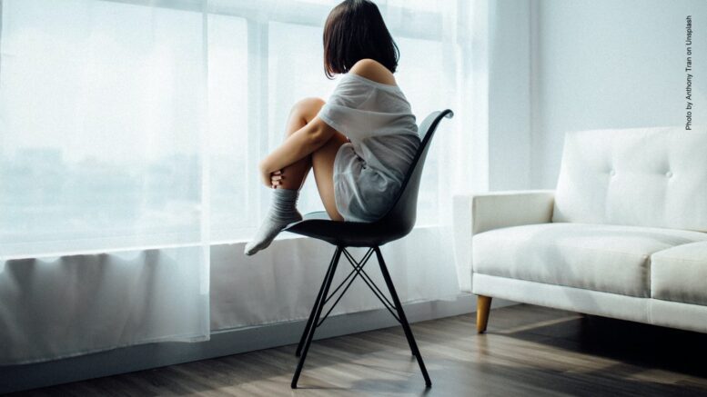 Frau sitzt auf einem Stuhl am Fenster