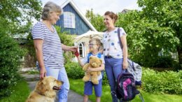 Mutter mit Kind wird im Ferienhof Olde von der Gastgeberin mit Hund begrüßt