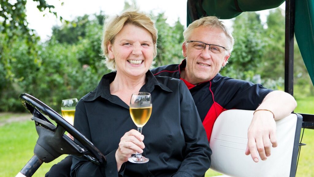 Susanne und Uwe Berger im Golfwagen mit Weinglas