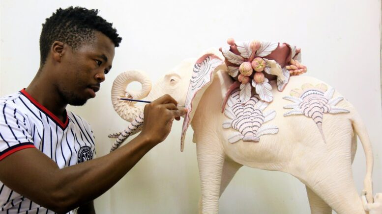 Afrikanischer Künstler bemalt Keramikfigur