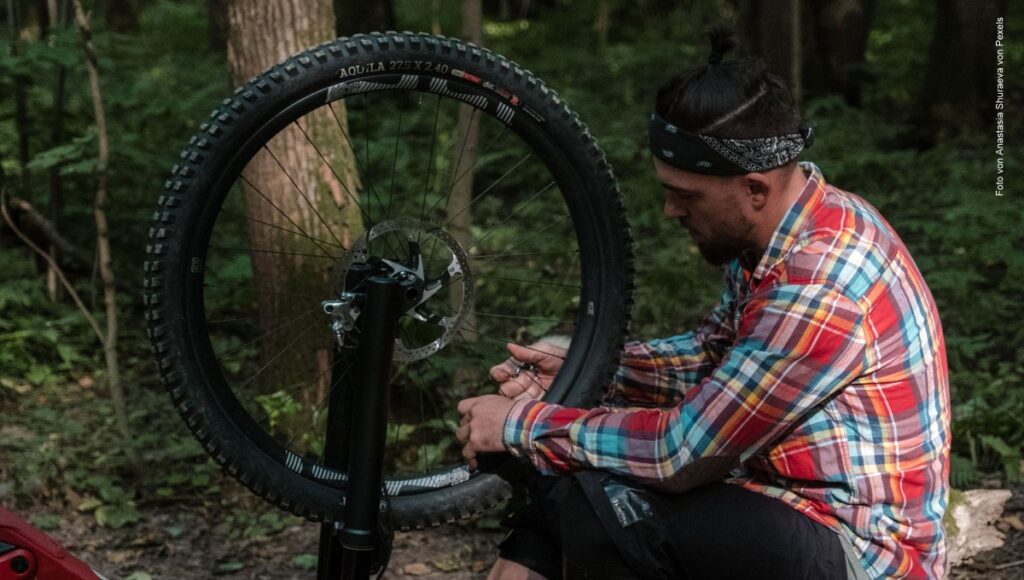 Mann repariert ein Fahrrad im Wald