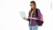 Studentin in karrierter Bluse stehend mit Laptop