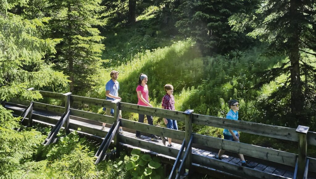 Familie geht über eine Holzbrücke im Wald