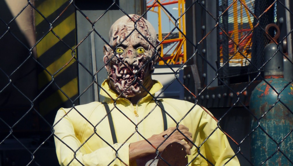Ein Zombie in gelben Overall an einem Schutzzaun