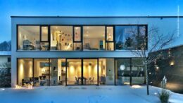 Modernes Einfamilienhaus im Winter mit Schnee bei Dämmerung