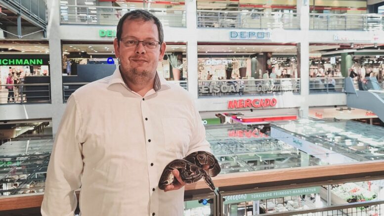 Tiertrainer Andre Weseloh steht mit einer Schlange im Shoppingzentrum Mercado